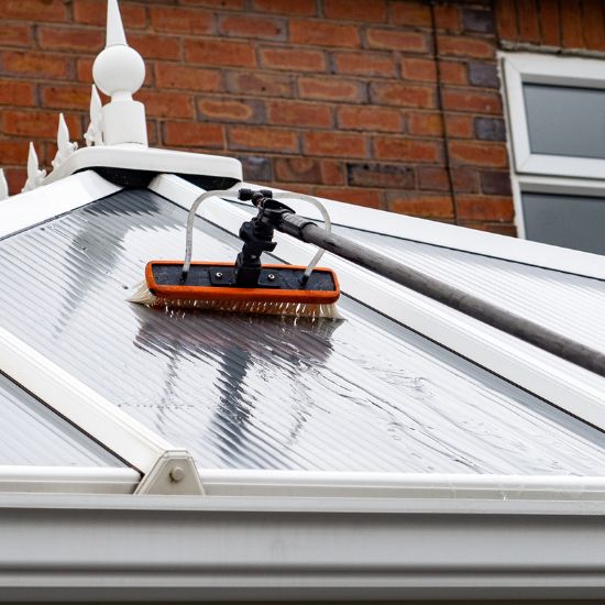 a upvc conservatory being cleaned by a window cleaner using a pole system